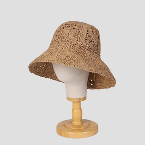 Handcrafted coffee brown straw bucket hat with hollow-out pattern on a display stand