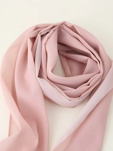Détail d'une écharpe en mousseline rose avec coutures fines et texture douce