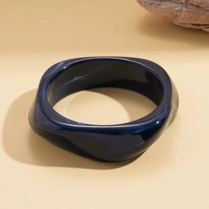 Macro shot of wide wavy blue resin bangle showing glossy finish and smooth textures
