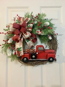 Close-up of a Christmas wreath with a red truck, pine branches and Merry Christmas ribbon