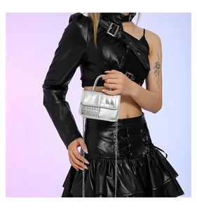 Detail of silver crocodile embossed mini square bag with metal chain on model