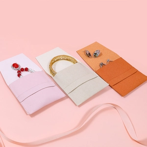 Microfiber envelope jewelry pouches in pink, cream, and orange with ribbon detail