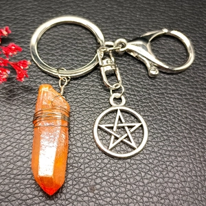 Natural orange crystal pillar keychain with star charm on black leather background