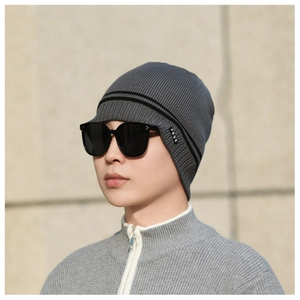 Close-up of grey knit beanie with black stripes and brand label on model side profile