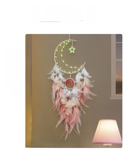Detail of dream catcher featuring crescent moon shape with feathers and tree of life charm