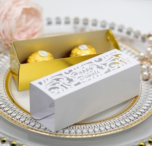 Detail der lasergeschnittenen Happy Diwali Geschenkbox in Weiß und Gold auf Teller