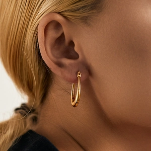 Close-up of minimalist gold plated geometric hoop earring with polished finish