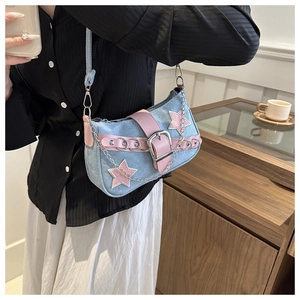 Detail of Y2K denim star underarm bag with pink leather trim and silver chain on model