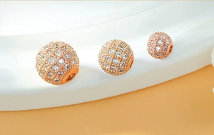 Detailed macro view of three rose gold micro-pave zircon round beads for DIY bracelets