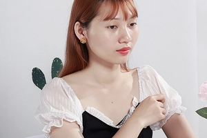 Close-up of a woman wearing gold hollow circular earrings with a polished metal finish