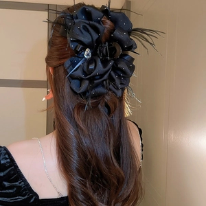 Detail of elegant black ribbon hair claw with feathers and a teardrop gemstone