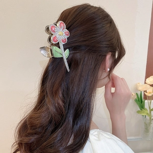Détail de la pince à cheveux fleur rouge avec strass portée sur les cheveux