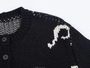 Close-up of black knit cardigan with white floral jacquard and matte round buttons