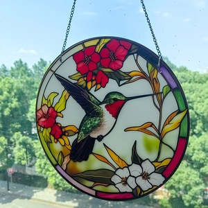 Detail of colorful hummingbird and flower suncatcher with iron chain on a window