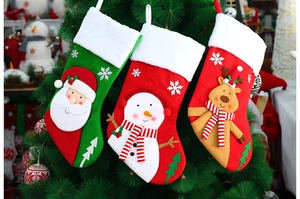 Close-up of three knitted Christmas stockings with Santa, snowman, and reindeer on a tree