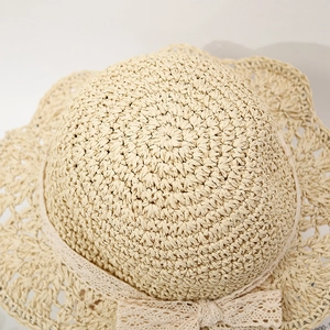 Detailed top view of beige straw hat featuring wave brim and elegant lace bow