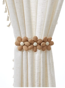 Detailed view of handmade khaki burlap flowers on beige curtains with fringe tassels