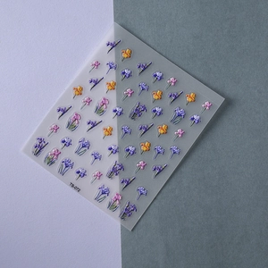 Detailed macro view of 3D embossed iris flower nail art stickers in purple and yellow