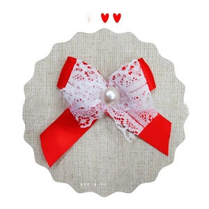 Close-up of red satin bow with white lace layers and a central pearl detail