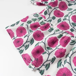 Détail du tissu à fleurs avec bourgeons roses, feuilles vertes et ourlet volanté