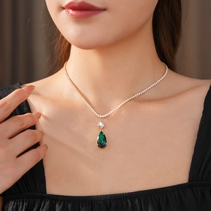 Close-up of gold pear-shaped green zircon pendant necklace on a female model neck