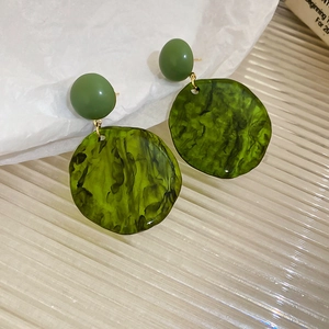 Close-up of olive green irregular resin earrings with golden metal marble textures