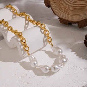 Détail d'une chaîne plaquée or 18 carats avec perles baroques sur fond blanc texturé