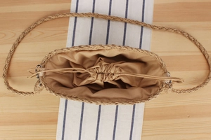 Vue à plat d'un sac en paille fait main avec doublure à cordon et bandoulière tressée