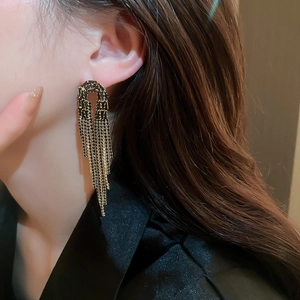 Close-up of long tassel earrings in black and gold finish worn by a model