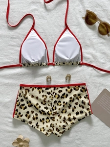 Flat lay of a sexy leopard print bikini set with red trim and high-waist bottoms on white fabric