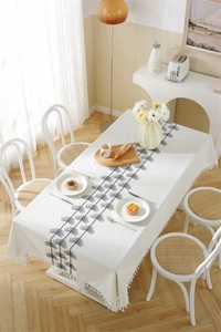 Detail of cream cotton linen tablecloth with black floral embroidery and tassel fringe