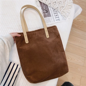 Close-up of brown corduroy tote bag with beige handles and golden rivet details