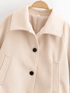 Detail of beige wool coat texture featuring black round buttons and lapel on wooden hanger