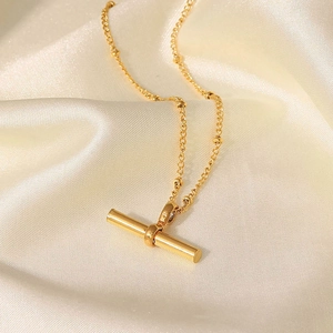 18K gold plated titanium anklet with minimalist T-bar pendant on white silk background