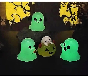 Close-up of luminous Halloween ghost and pumpkin figurines glowing in dark night scenery