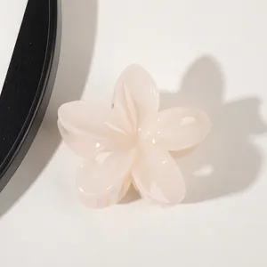 Detail of a creamy beige flower hair claw clip with a glossy finish and layered petals