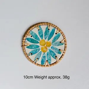 Detail of 10cm handwoven rattan coaster with decorative blue and yellow daisy shell inlay