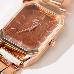 Vista macro di orologio ottagonale in oro rosa con quadrante effetto legno e cinturino