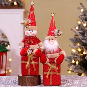 Detail of plush Santa and Snowman dolls sitting on red gift box bases for Christmas decor