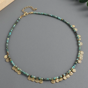Collar boho de cuentas turquesas con colgantes de discos dorados en fondo oscuro