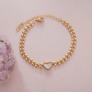 Detail of gold leaf-link chain bracelet with a white heart charm and adjustable clasp