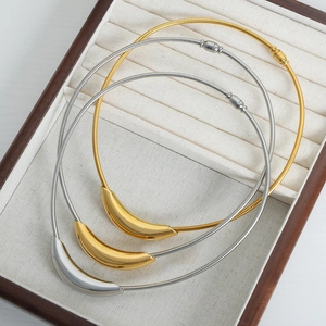 Three-piece minimalist geometric gold and silver curved pendant necklaces on a display tray