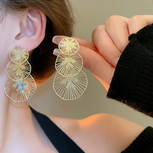 Gros plan de boucles d'oreilles dorées irrégulières avec motifs radiaux texturés