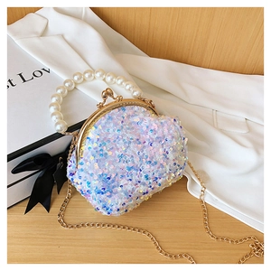 Detail of sequin shell bag with pearly handle and gold chain on wooden surface