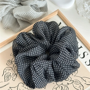 Detail of high-elastic black mesh scrunchie with white polka dots on aesthetic background