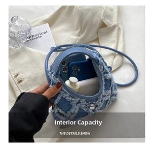 Detail showing the internal capacity of the denim crescent bag with a metal twist lock