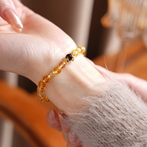 Close-up of a beaded bracelet with yellow citrine beads and red garnet floral detail