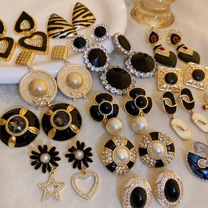 Flat lay of vintage style black enamel and gold alloy earrings with pearls and rhinestones