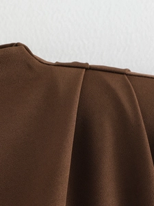Detail of dark brown padded shoulder top showing pleated craftsmanship and twill fabric texture