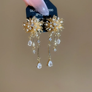 Detail of gold floral tassel earrings featuring imitation pearls and zircon accents